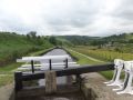 The Diggle Flight is unusual both for its slanted paddles that can be very hard to operate, but also for its single bottom gates. The tough paddles are actually quite large and fully opening them when filling the lock creates a lot of turbulence which is aggravated by the flat bottom gate which reflects the turbulence. A pair of gates form a mitre which deflects and weakens the the rush of water flowing in from the top paddles. - Location: Diggle - Canal: Huddersfield Narrow