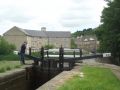 Lock 9E - getting down amongst the mills of Huddersfield where the building on the left has been cleaned and renovated for housing use. Son Martin wields the windlass as we head for the mooring space beyond the lock for a well-earned lunch.  - Location: Huddersfield - Canal: Huddersfield Narrow